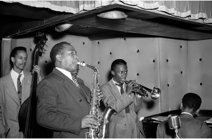 Miles Davis aux côtés de Tommy Potter, Charlie Parker, Max Roach (partiellement caché par Parker) et Duke Jordan (de gauche à droite), au Three Deuces, New York, 1947, William P. Gottlieb (via Wikimedia Commons)